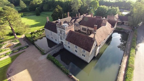 A bird's-eye view of the house at Ightham Mote, Kent, showing the square building surrounded by a moat and gardens